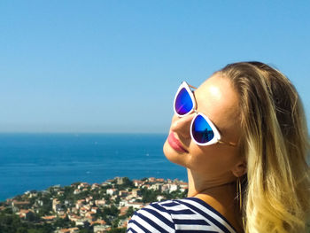 Portrait of woman wearing sunglasses against clear blue sky