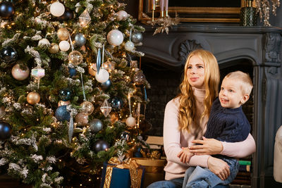 Mother hugs her son near the christmas tree