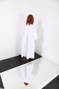 Rear view of woman standing on white table