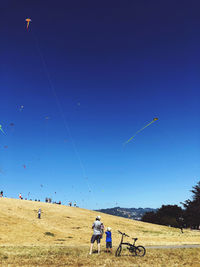 People on field against clear blue sky