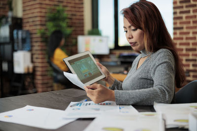 Businesswoman using digital tablet while sitting on table