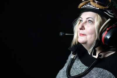 Woman wearing aviators cap against black background