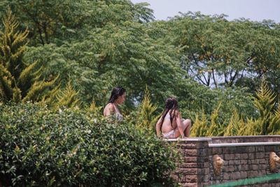 Friends standing by plants against trees