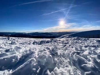 Snow covered landscape against blue sky