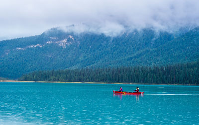 People in boat on lake against mountain