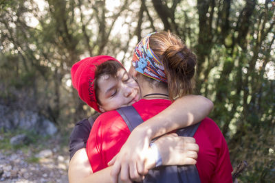 Two young people hugging outdoors in a forest