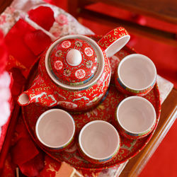 High angle view of tea cups with red teapot on table