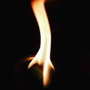 Close-up of lit candle against black background