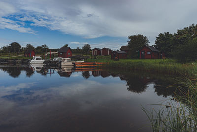 Reflection of trees and houses on lake against sky