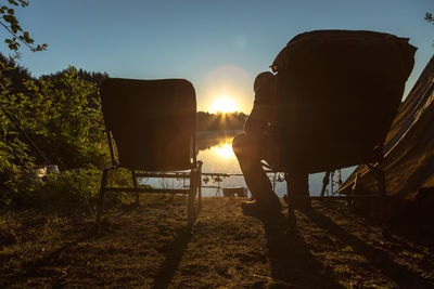 Rear view of people sitting on chair at sunset