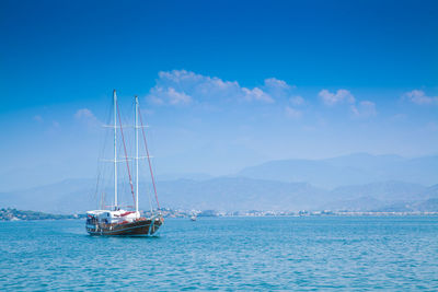 Sailboat sailing in sea against blue sky