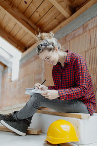Woman working while sitting against wall