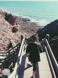 Rear view of woman standing by sea against sky