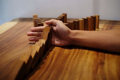 Cropped image of man stopping dominoes on table