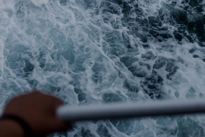 Cropped hand holding railing against sea