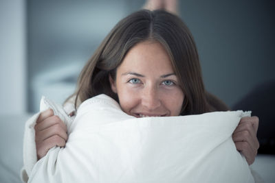 Portait of happy young woman lying on bed