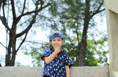 Portrait of boy smiling against trees