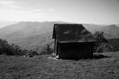 Built structure on field by mountains against sky