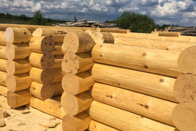 Stack of firewood against sky on sunny day