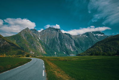 Road leading towards mountains against sky