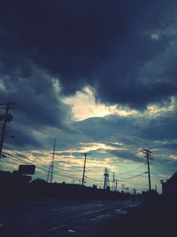 Low angle view of electricity pylon against cloudy sky