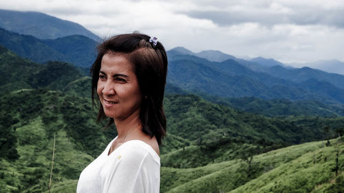 Portrait of young woman standing against mountain