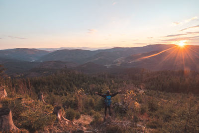 Amazing moment at sunrise as a hiker celebrates his climb up the mountain and completing 