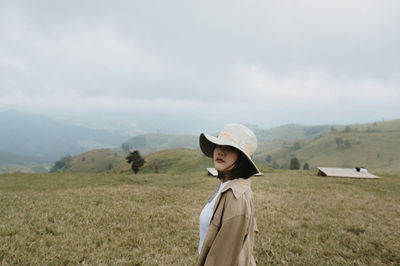 Portrait of woman standing on field against sky