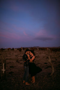 Woman standing on field against sky during sunset