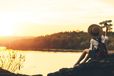 Full length of boy with arms raised against sky during sunset