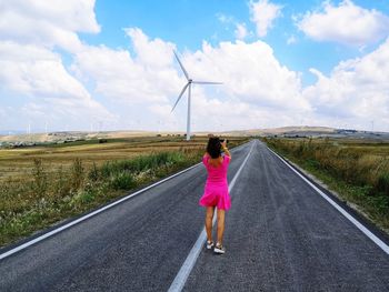 Rear view of woman standing on road against sky