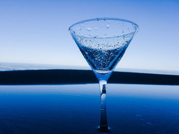 Close-up of glass of water against blue sky