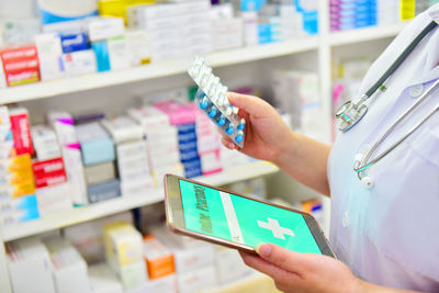 Midsection of person holding mobile phone at store