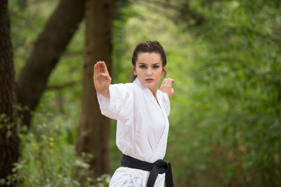 Portrait of young woman standing against tree