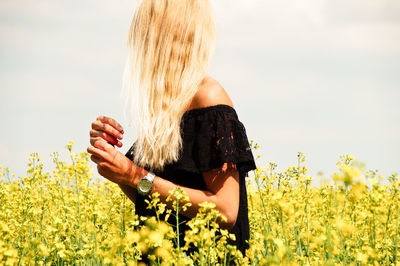 Young woman standing on oilseed rape field