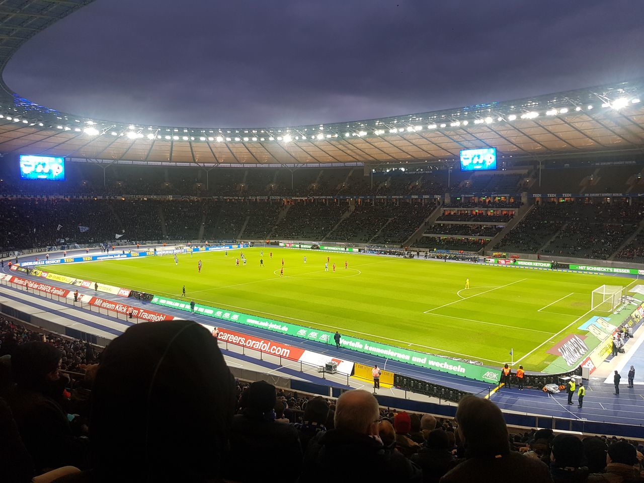 GROUP OF PEOPLE LOOKING AT ILLUMINATED STADIUM