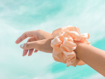 Close-up of woman holding hands against sky