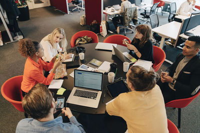 High angle view of multi-ethnic coworkers discussing strategy while sitting conference table in office