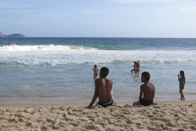 Rear view of people on beach against sky