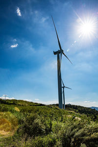 Low angle view of windmill on field against sky