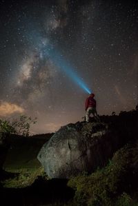 Man standing on rock against sky at night