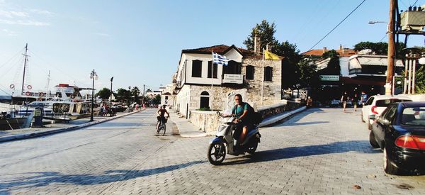 Man ridding motorcycle on street against buildings in city