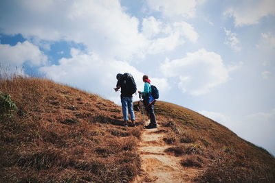 Rear view of men walking on road against sky