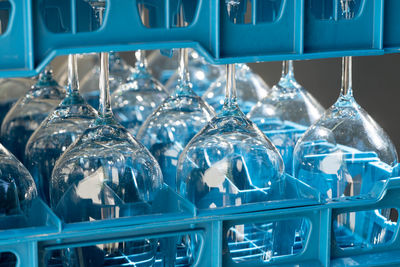 Blue plastic boxes with shiny wineglasses for restaurant standing upside-down and reflecting light