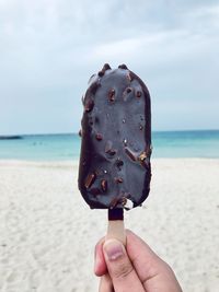 Close-up of hand holding ice cream on beach