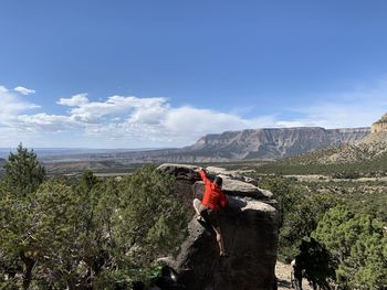 Rear view of man standing on mountain against sky