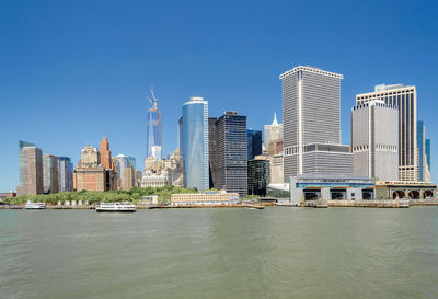 Modern buildings by river against clear sky