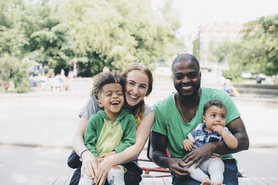 Portrait of happy parents with children sitting at park