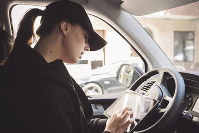 Side view of driver using digital tablet in truck