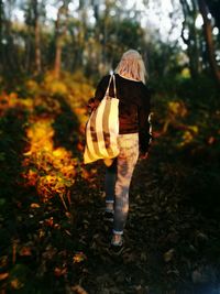 Rear view of woman walking on field at park